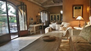 Un salon chaleureux avec une table en bois, un canapé et un fauteuil. Une fenêtre offre une vue sur l’extérieur.