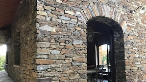 Un intérieur aux murs de pierre, avec une porte en arc donnant sur un espace repas.