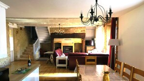 Un amplio espacio de sala con chimenea, una mesa de comedor y una encimera de cocina.