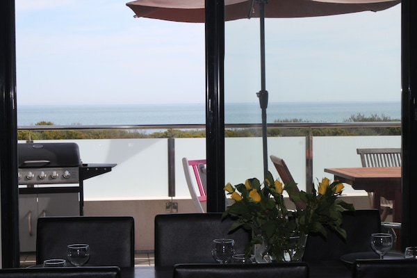 Terrasse donnant vue sur mer et jardin avec un barbecue table et chaises en teck