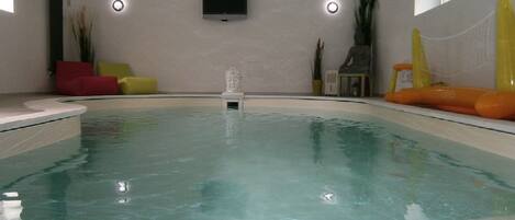 A swimming pool with a small statue in the center, surrounded by yellow and orange lounge chairs.