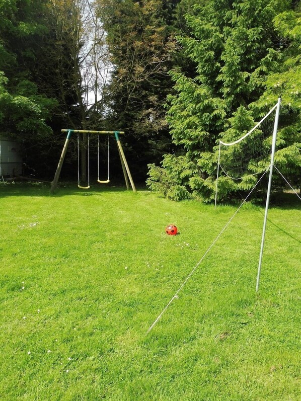 A grassy yard with a swing set and a soccer ball.