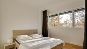 Makuuhuoneessa on puinen sänky, yöpöytä ja ikkuna, josta avautuu näkymä puihin.