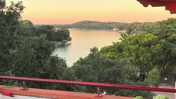 A balcony with a view of a lake, surrounded by greenery, and a red railing. - Magnificent Lake View, Hossegor City Center, 10 min walk to the Ocean, Large Terrace (Soorts-Hossegor)
