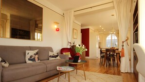 A living room with a sofa, a small table with a magazine, and a vase with flowers. - Magnificent Lake View, Hossegor City Center, 10 min walk to the Ocean, Large Terrace (Soorts-Hossegor)