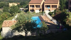 Edificio residencial con piscina, rodeado de vegetación y colinas.