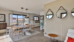 En moderne stue med spiseplads, store vinduer og udsigt over byen.
