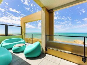 Ein Balkon mit türkisfarbenen Stühlen und Blick auf den Strand.