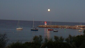 Un paysage côtier avec des bateaux ancrés près d’un phare.