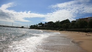 Une plage avec un ciel dégagé, une eau calme et une jetée en bois qui s’avance dans la mer.