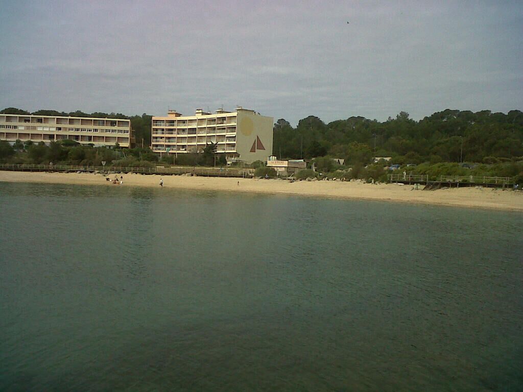 A beachfront hotel with multiple floors, a sandy beach, and a calm sea.