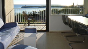 Un balcon avec vue sur la mer, un canapé, une table à manger et une chaise.