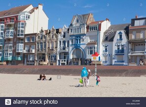 Une plage avec des gens et des bâtiments en arrière-plan.