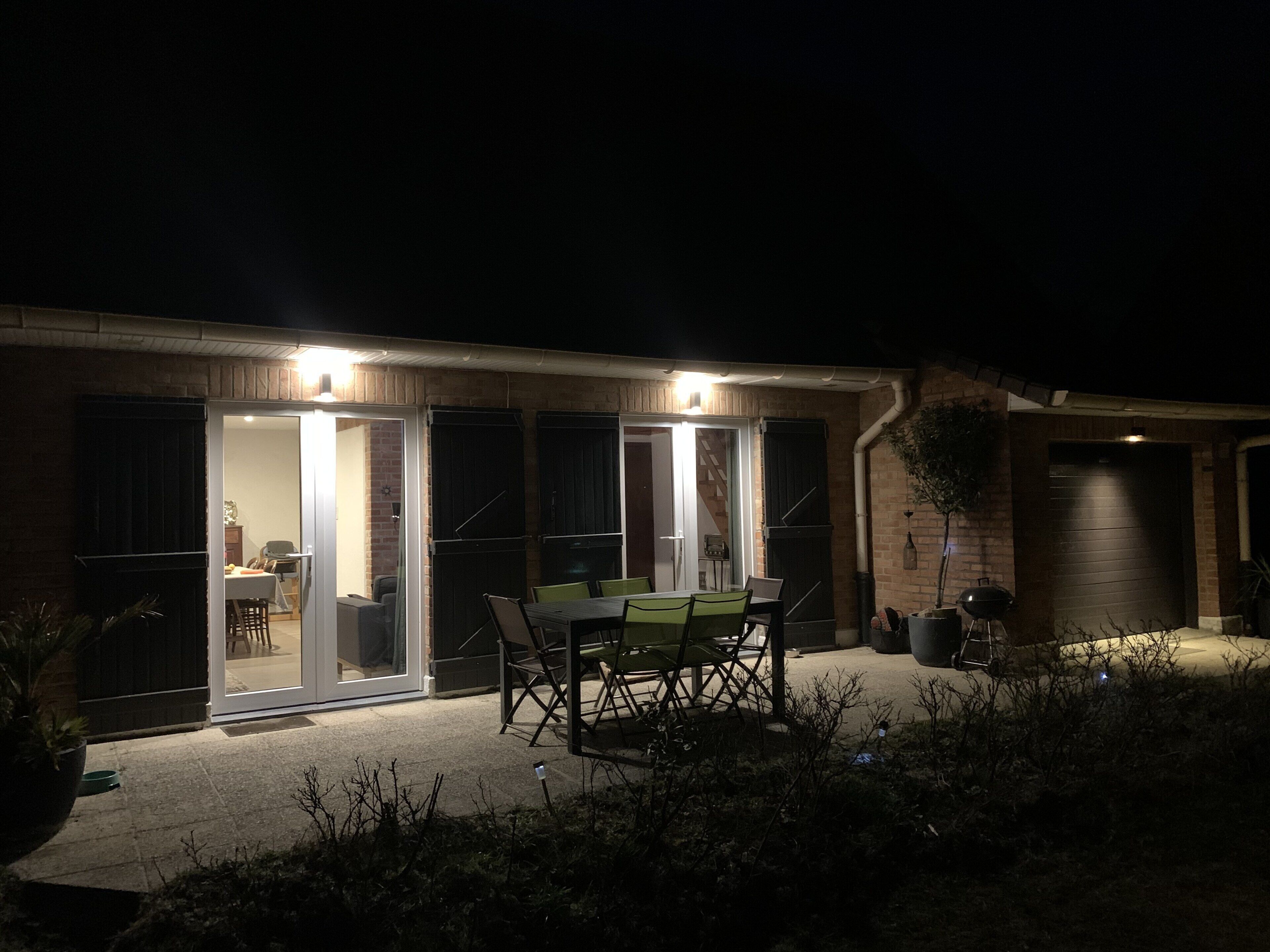 Une terrasse extérieure avec une table et des chaises, un barbecue et un mur en briques.