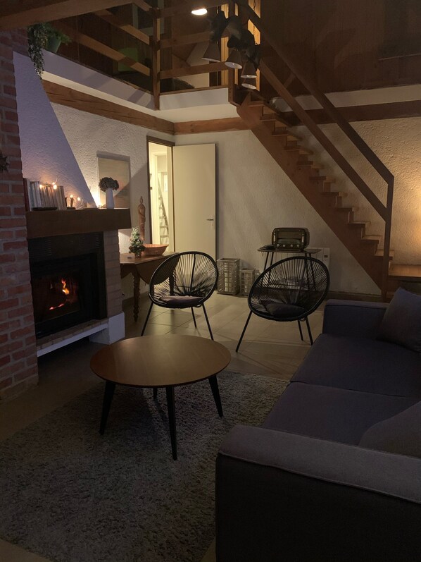 Un salon chaleureux avec une cheminée, un escalier et un canapé.