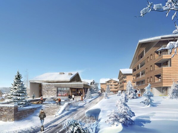 A modern ski resort with multi-story buildings, snow-covered trees, and a clear sky.