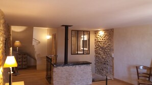 Een ruime woonkamer met een stenen muur, een open haard en een houten vloer.