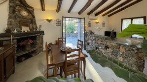 Un coin repas agrémenté d’une cheminée en pierre, d’une table à manger en bois et de chaises.