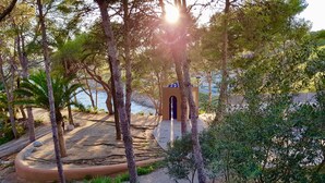 Un parc côtier doté d’une promenade dallée, de palmiers et d’un petit bâtiment surmonté d’une arche violette.