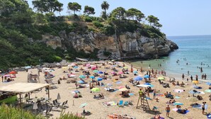 Une plage bondée, avec de nombreux parasols et des gens qui profitent de la mer.
