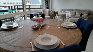 Une table de salle à manger ronde en bois, mise avec des assiettes, des verres et des couverts.