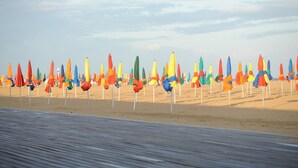 Une plage bordée de rangées de parasols colorés.