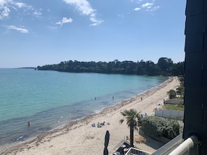 A beach with clear water, a sandy shore, and a forested hill in the background. - Apartment 180° sea view direct beach access (Fouesnant)
