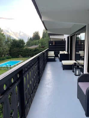 A balcony with a pool, outdoor furniture, and a view of mountains. - Light in chalet apartment, beautiful view of Mont Blanc, 200m from the slopes (Chamonix-Mont-Blanc)