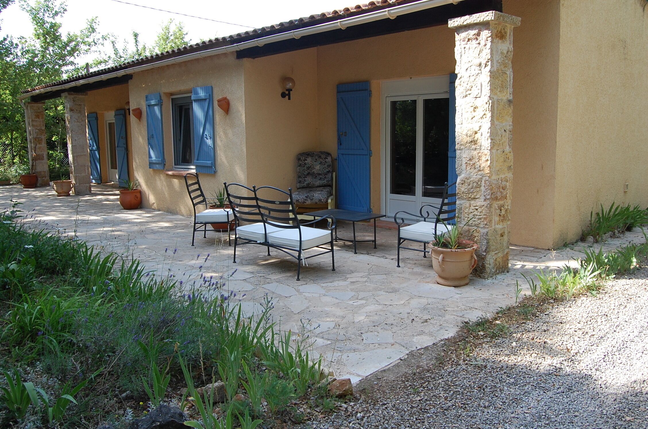 Une terrasse avec des meubles d’extérieur, un sol en pierre et des plantes en pot.
