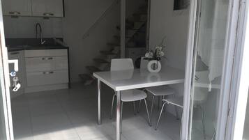 Une cuisine moderne avec des meubles blancs, un évier en acier inoxydable et un escalier menant à l’étage supérieur.