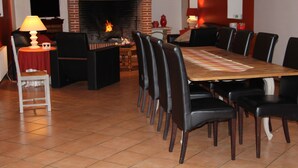 Un coin repas avec une cheminée en briques, une table en bois et des chaises noires.