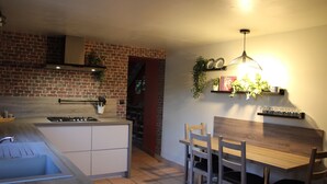Une cuisine avec un mur en briques, une table à manger en bois et des chaises.