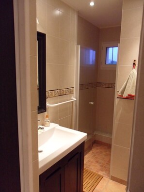 Un baño con lavamanos blanco, espejo y toallero.