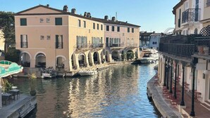 Un canal con un edificio de ventanas arqueadas y una embarcación amarrada cerca.