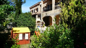Un edificio in pietra dal fascino tradizionale, con numerosi balconi e un camino, immerso nel verde.