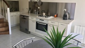 Una cocina moderna con armarios blancos, electrodomésticos de acero inoxidable y una estufa a gas.