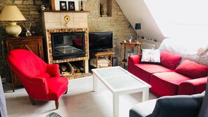 Una sala de estar acogedora con chimenea, muebles rojos y un televisor.