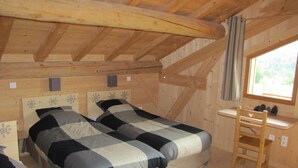 Ein Holzhütten-Zimmer mit zwei Betten, einem Schreibtisch und einem Fenster.