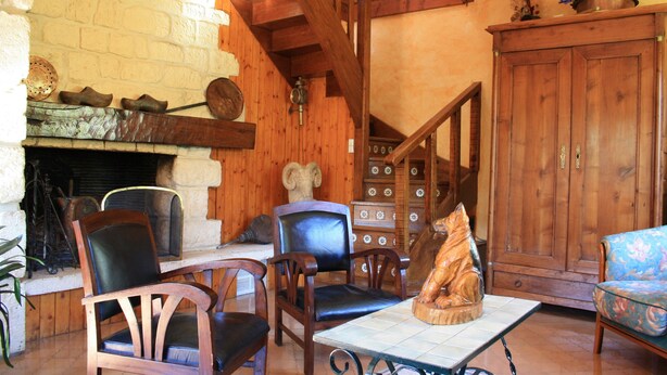 A rustic interior with a fireplace, wooden furniture, and a staircase.