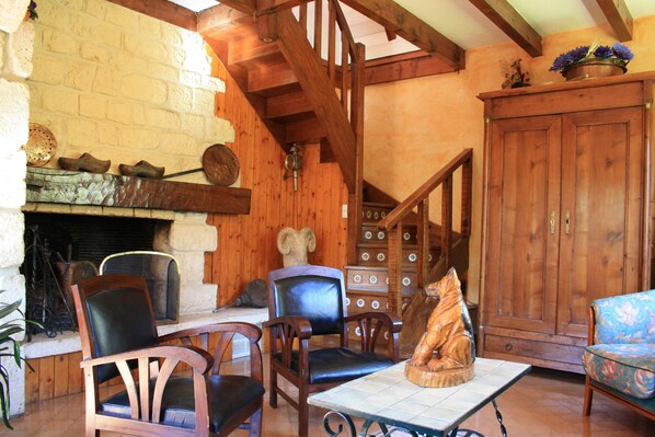 Un interior rústico con chimenea, muebles de madera y una escalera.