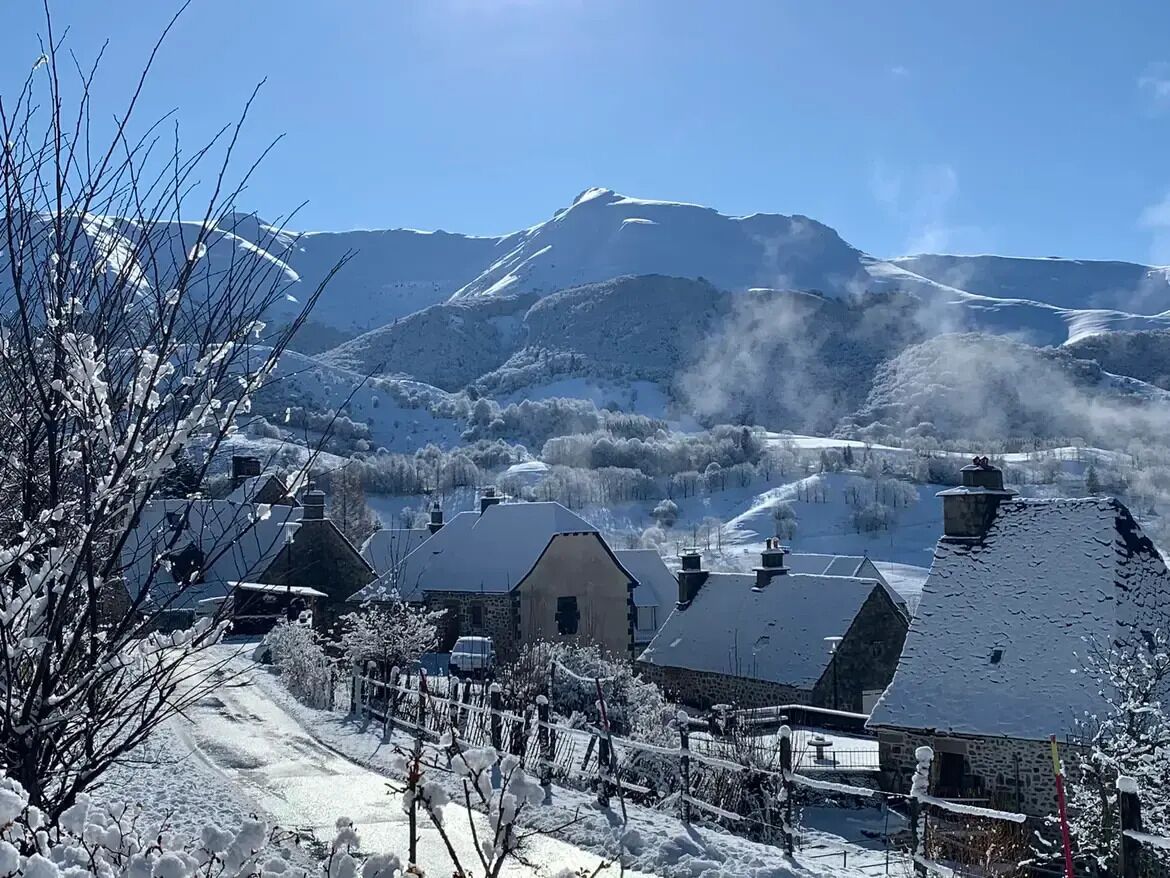 A snow-covered village with houses and a mountain in the background.