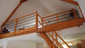 Een kamer in loftstijl met houten details, een schuine kap en een balkon.