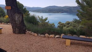 Un banco y un cartel cerca de un lago, con vistas a montañas.