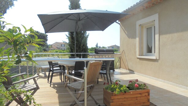An outdoor patio with a table, chairs, a grill, and a wooden planter with flowers. - House in Saint Victor la Coste in Provence, between Avignon and Pont du Gard (Saint-Victor-La-Coste)