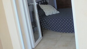 A room with a bed, a wooden wardrobe, and a sliding glass door leading to an outdoor area. - House in Saint Victor la Coste in Provence, between Avignon and Pont du Gard (Saint-Victor-La-Coste)