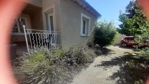 A house with a gravel driveway, a white metal gate, and a red car parked on the street. - House in Saint Victor la Coste in Provence, between Avignon and Pont du Gard (Saint-Victor-La-Coste)