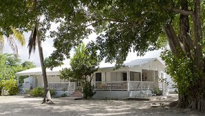 A white building with a porch and covered outdoor seating area. - Large family home with private beach  (Sainte Anne)