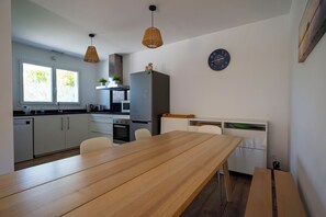 Une cuisine moderne avec une table à manger en bois, des meubles blancs et un four encastré.