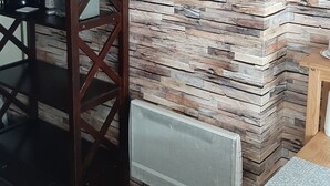 A room with a stone wall, a wooden cabinet with photos, a coffee maker, and a radiator. - rent studio center of the village 2 people (Cauterets)