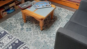 A cozy attic room with a TV, a small table with a board game, a patterned rug, and a sofa. - rent studio center of the village 2 people (Cauterets)